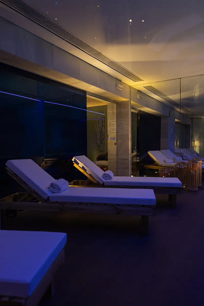 Sala de spa moderna con camillas iluminadas y luces azules al atardecer