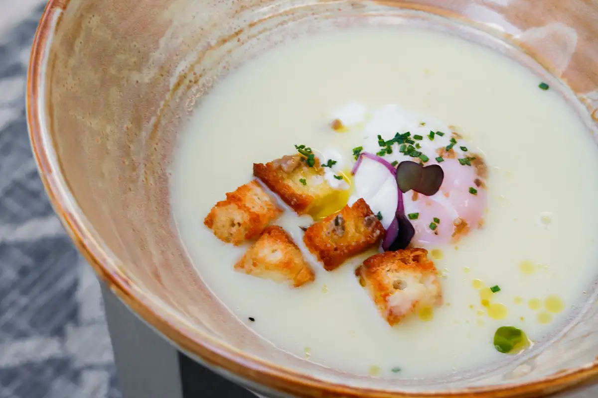 Plato de crema con trozos de pan, ceboll&iacute;n y adorno de vegetales.