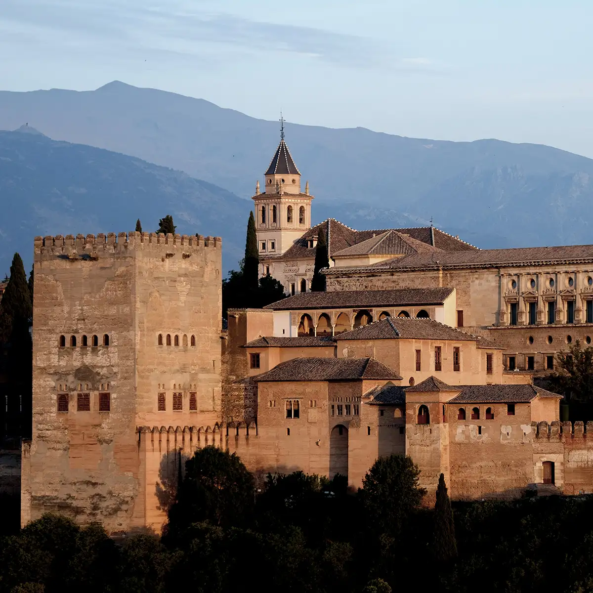 Alc&aacute;zar y catedral con torre sobre murallas, monta&ntilde;as al fondo