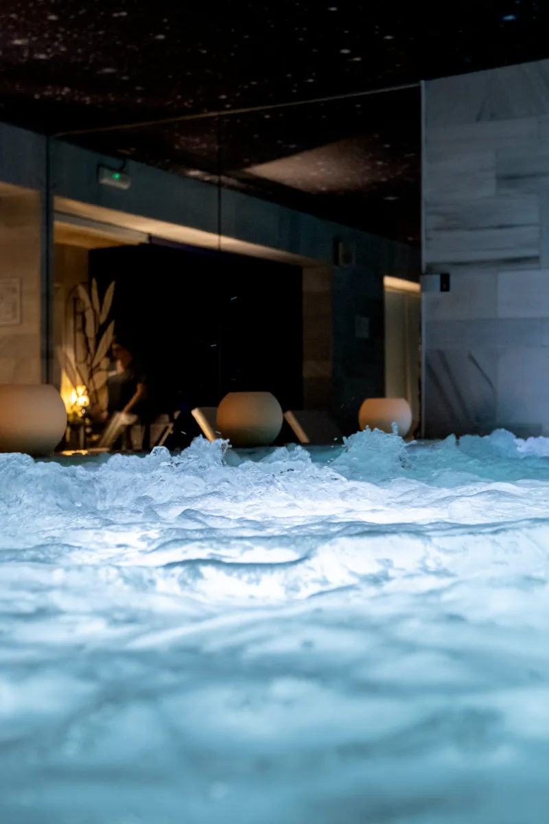 Jacuzzi con espuma y velas en un ambiente nocturno de spa.