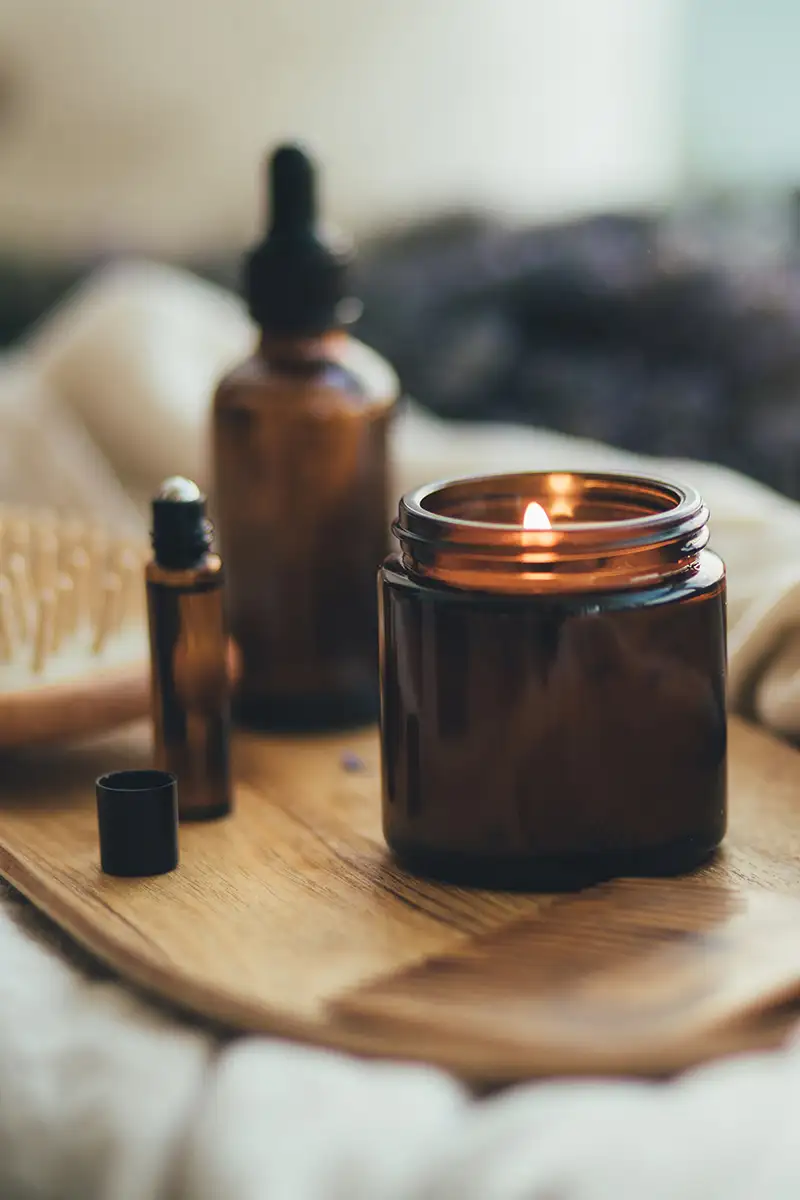 Velas en frascos de vidrio con llamas sobre una tabla de madera, ambiente c&aacute;lido