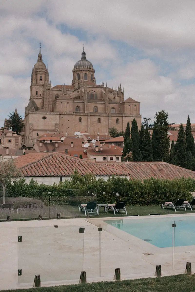 Vista de una catedral y una piscina con tumbonas al aire libre