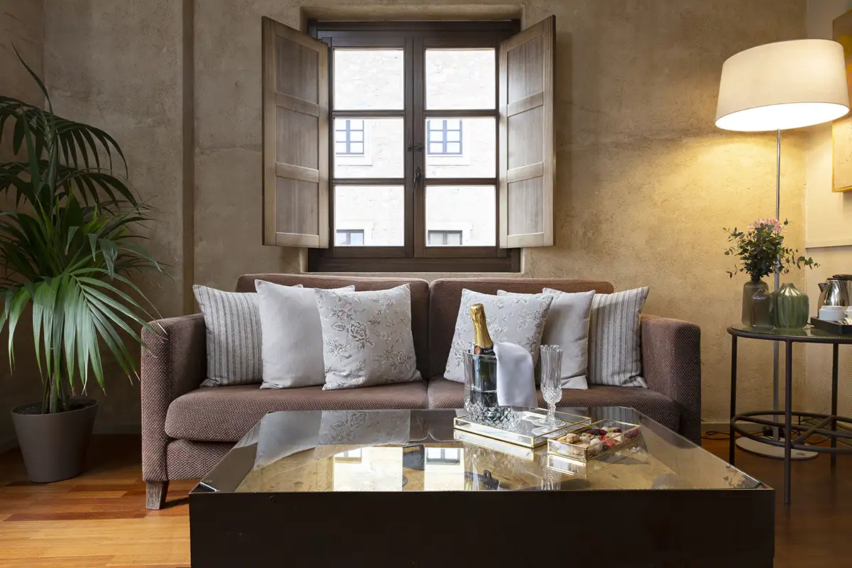 Sala de estar elegante con sof&aacute;, mesa de centro y l&aacute;mpara junto a ventana