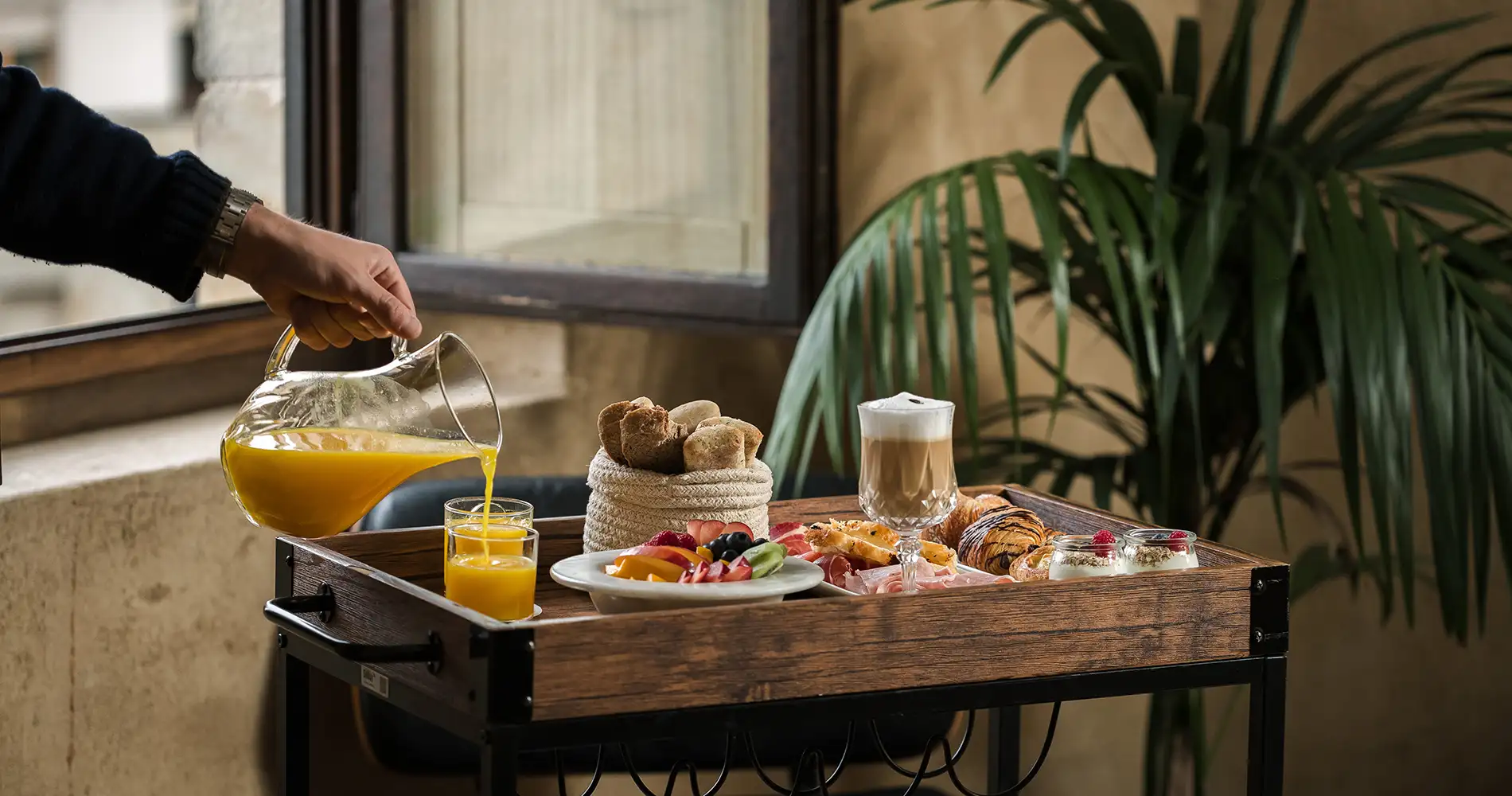 Sirve una jarra de jugo en una bandeja con desayuno y vasos en la mesa