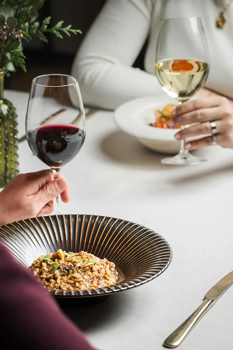 Cena elegante con vinos y plato de comida en un mantel blanco