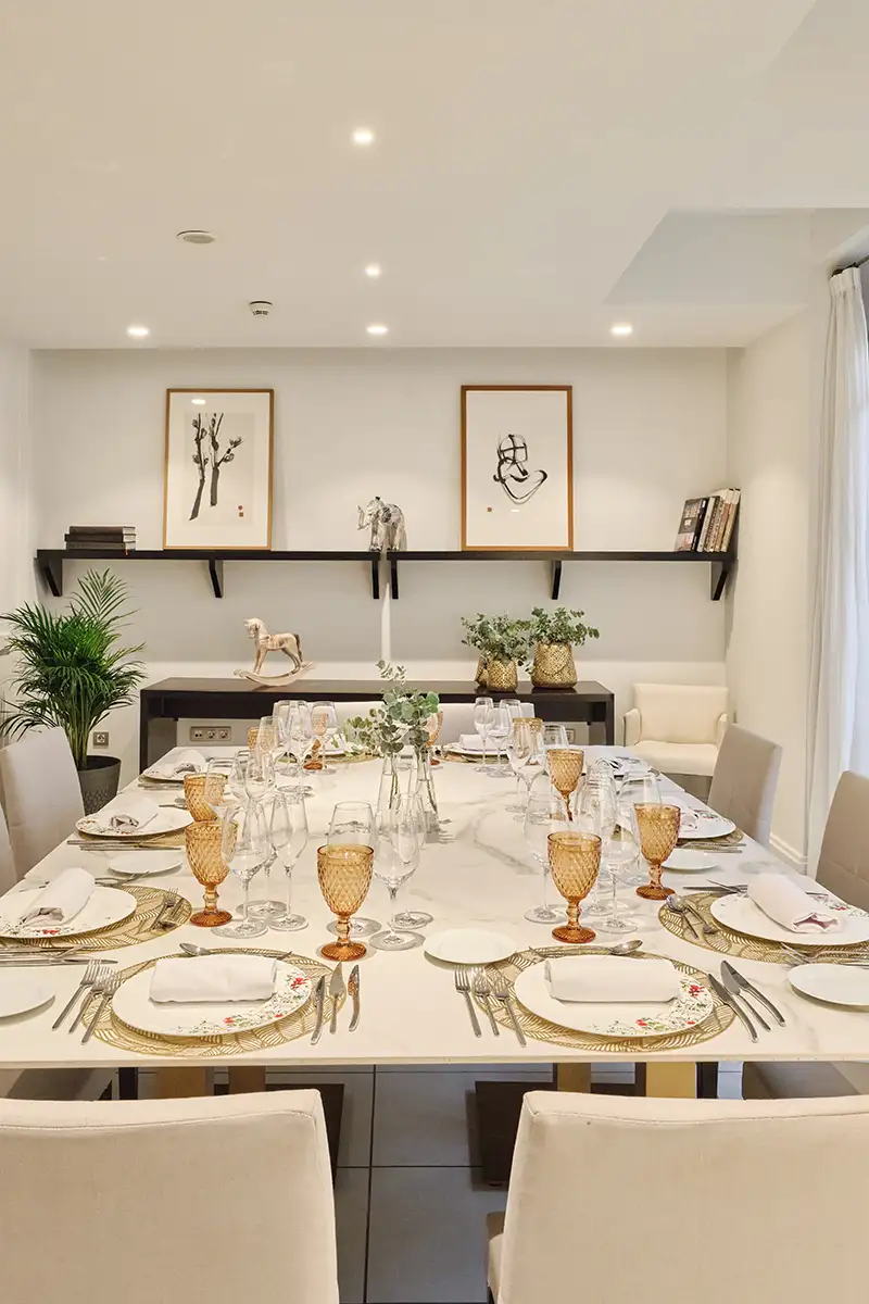 Mesa de comedor preparada con copas y decoraci&oacute;n en sala luminosa