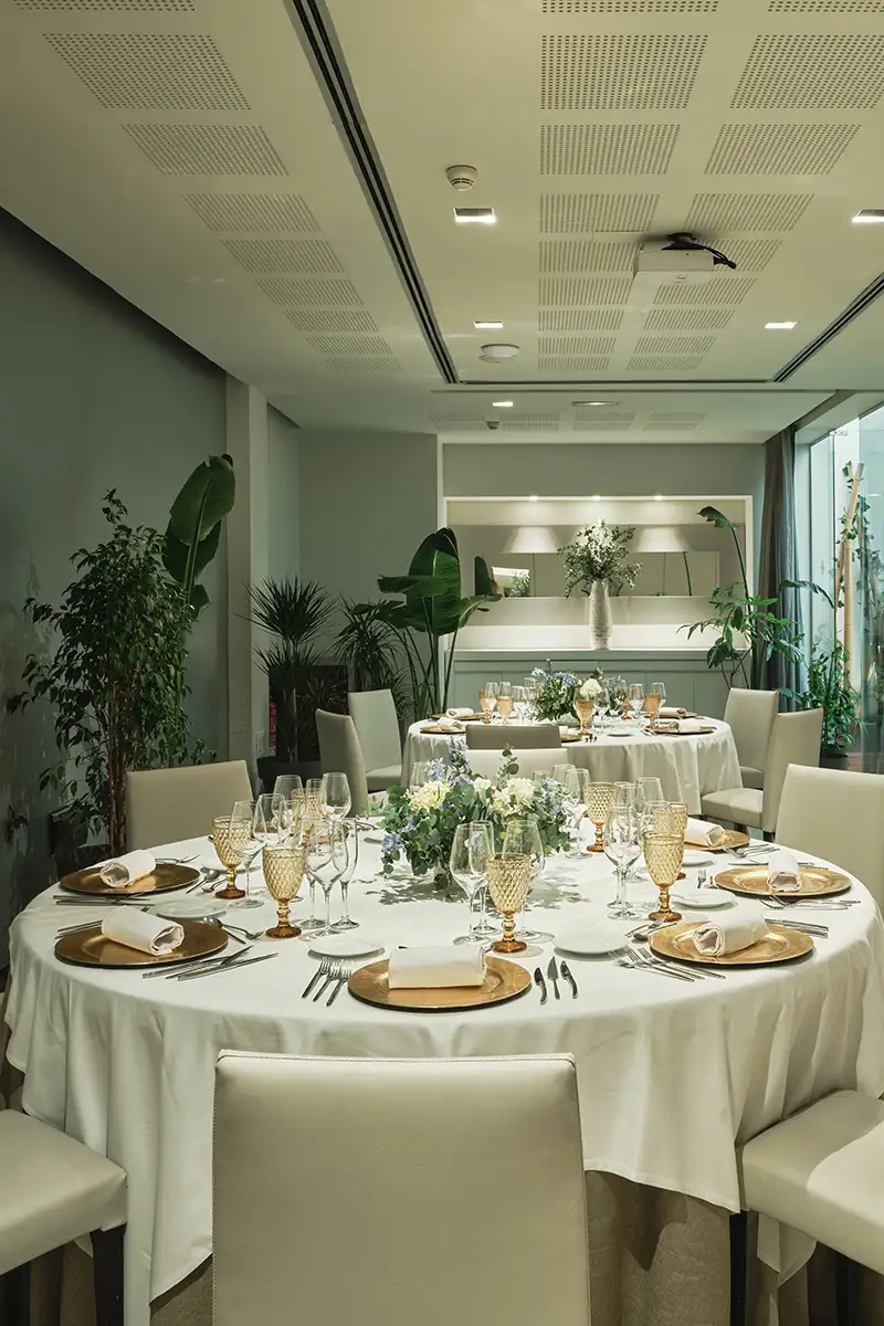 Mesa de banquete elegante con copas y flores en un sal&oacute;n luminoso
