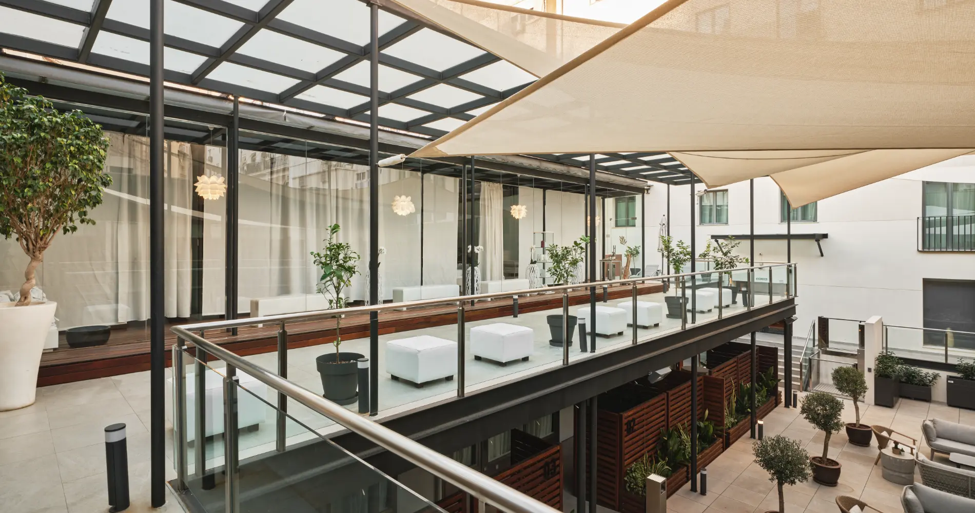 Terraza interior moderna con p&eacute;rgola y mesas, sillones blancos y jardines