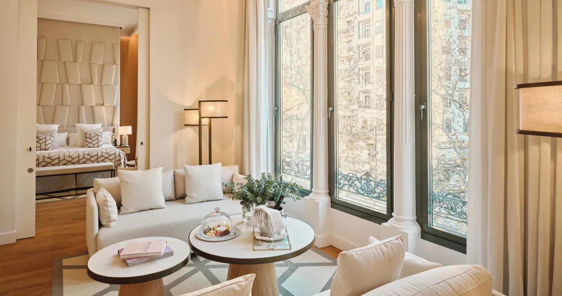 Sala de estar con sof&aacute; blanco, mesas redondas y grandes ventanas al exterior