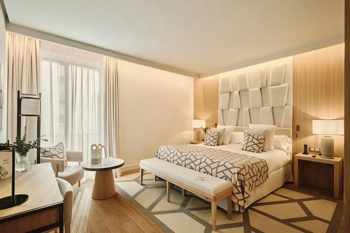 Habitaci&oacute;n moderna con cama, cabecero acolchado y cortinas blancas