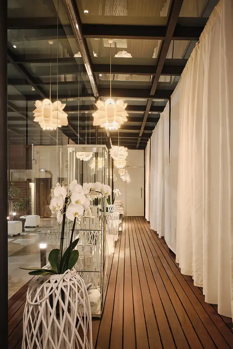 Pasillo elegante con l&aacute;mparas colgantes y orqu&iacute;deas blancas en maceta decorativa