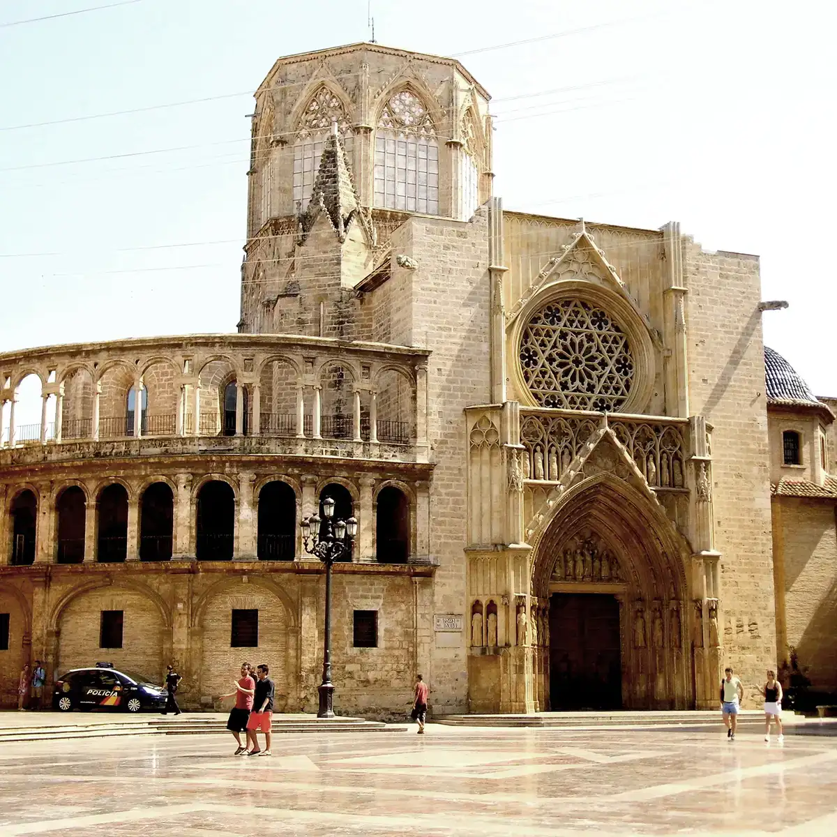 Catedral de piedra con ventanales g&oacute;ticos y plaza; turistas y patrulla policial