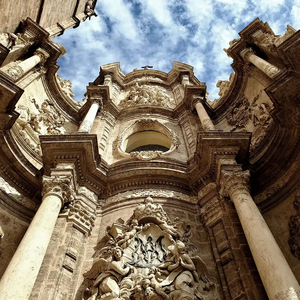 Interior de bas&iacute;lica barroca con columnas, esculturas y c&uacute;pula, cielo nublado