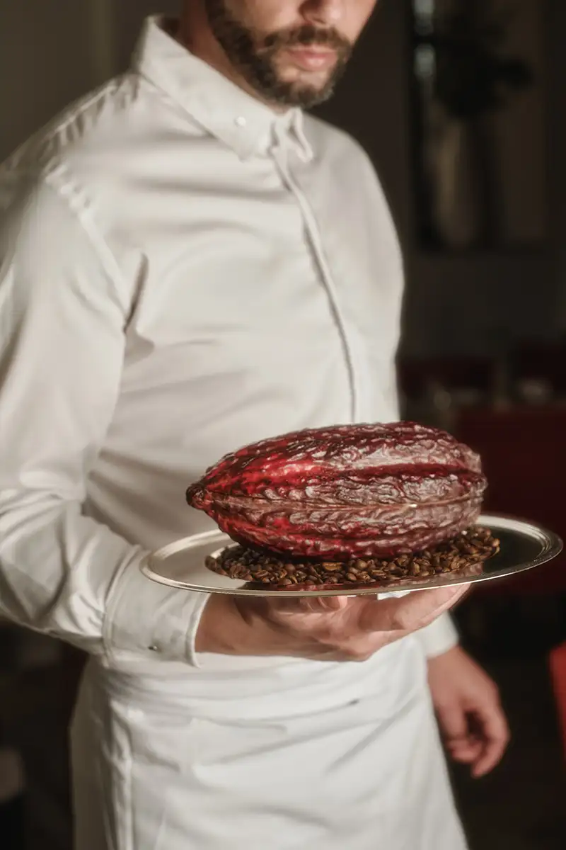 Chef con bata blanca sosteniendo una bandeja con un cacao de chocolate rojo