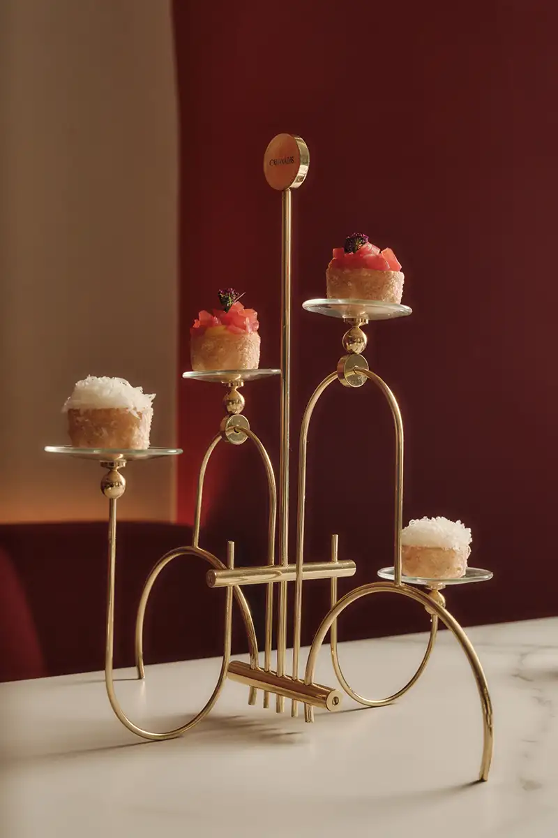Copa de postres en soporte dorado con flores de frutas, sobre m&aacute;rmol