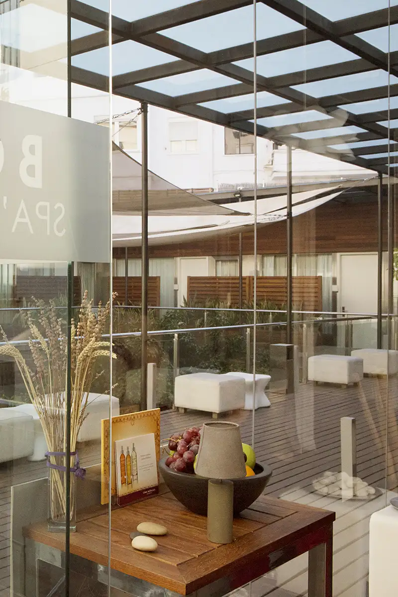 Terraza moderna con mesa de madera, frutas y sillas bajo una p&eacute;rgola met&aacute;lica