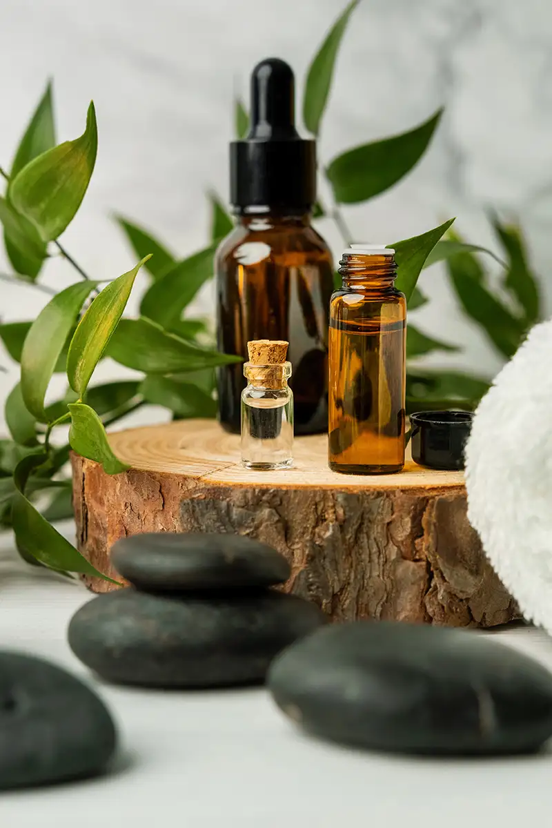 Aceites esenciales en frascos &aacute;mbar con hojas verdes y piedras spa