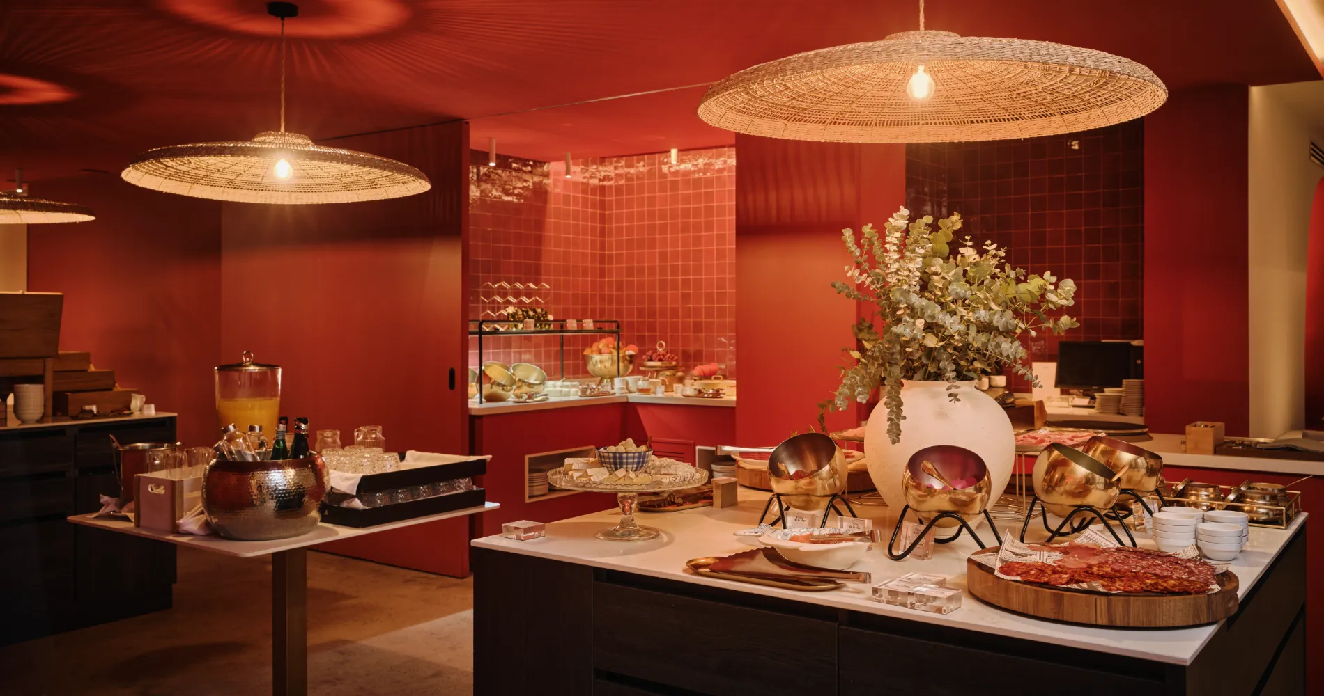 Buffet con mesas de servicio, flores y l&aacute;mparas colgantes en sala roja