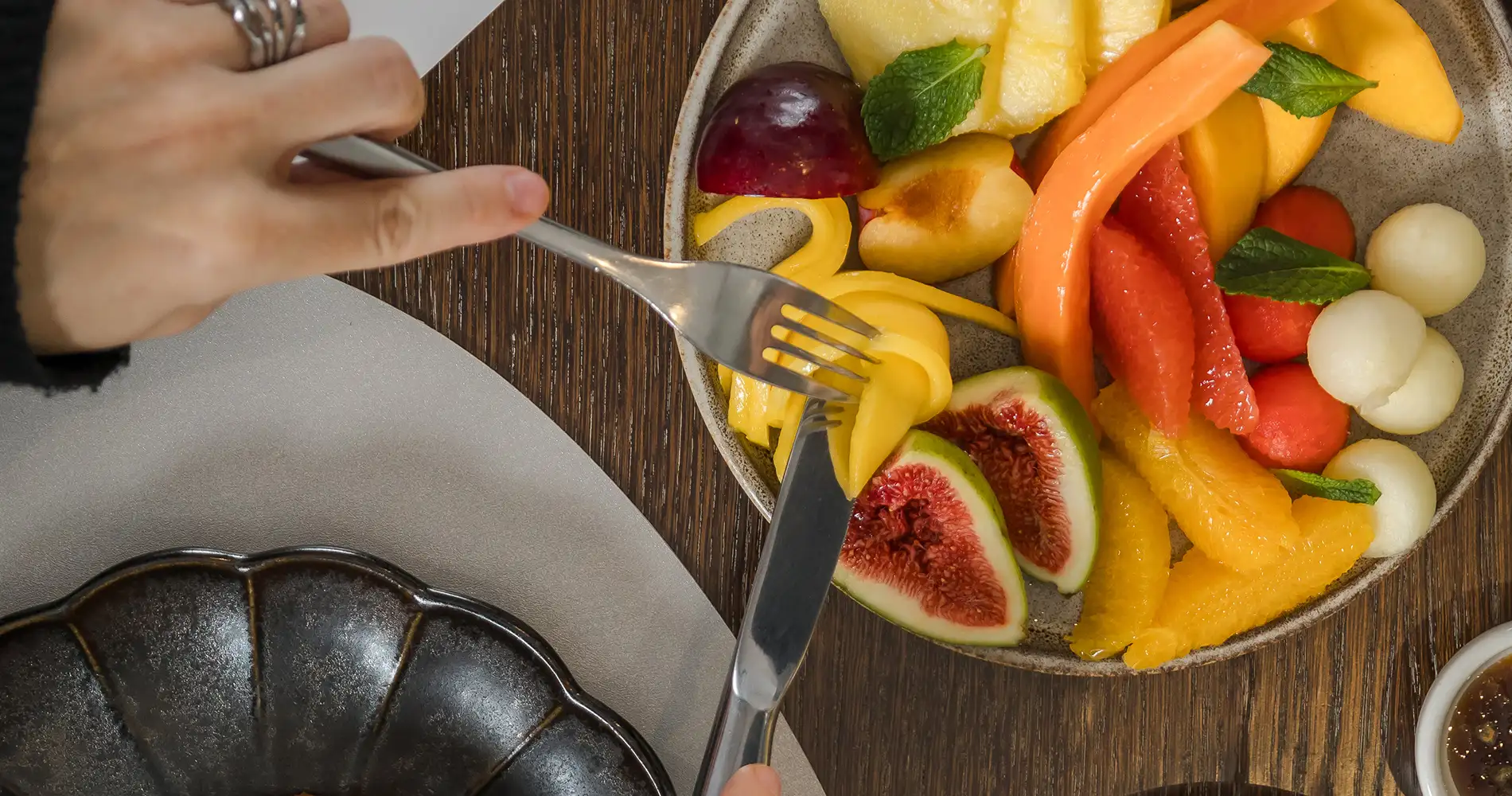 Corte de frutas frescas en un plato con tenedor y cuchillo sobre mesa