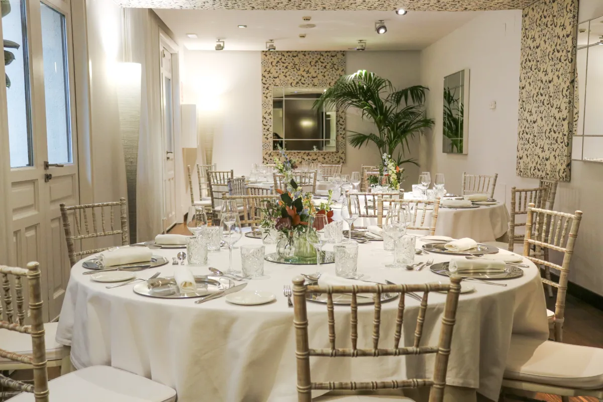 Sala de eventos con mesa puesta, sillas de ca&ntilde;a y decoraci&oacute;n floral