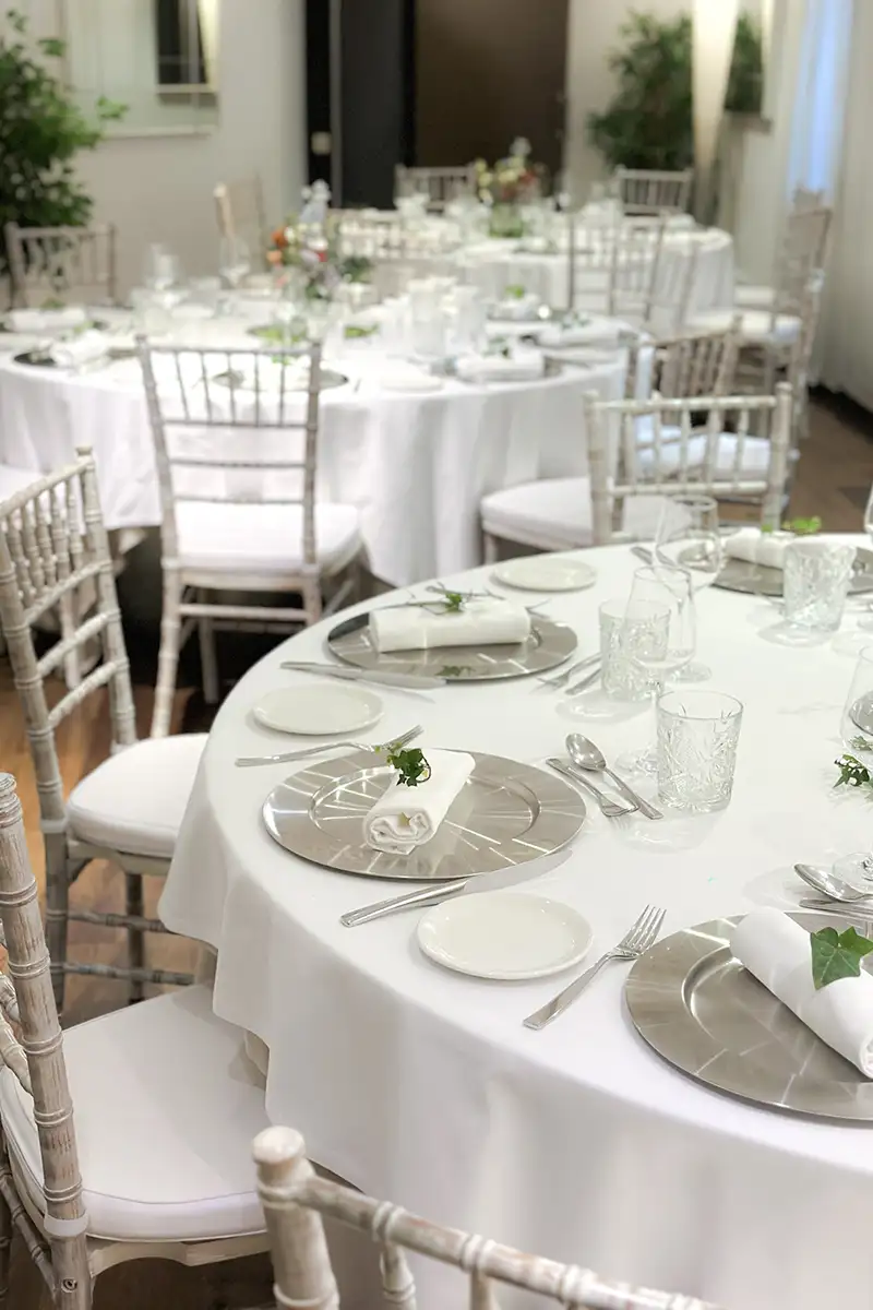Mesa de banquete con manteles blancos y vajilla para evento elegante