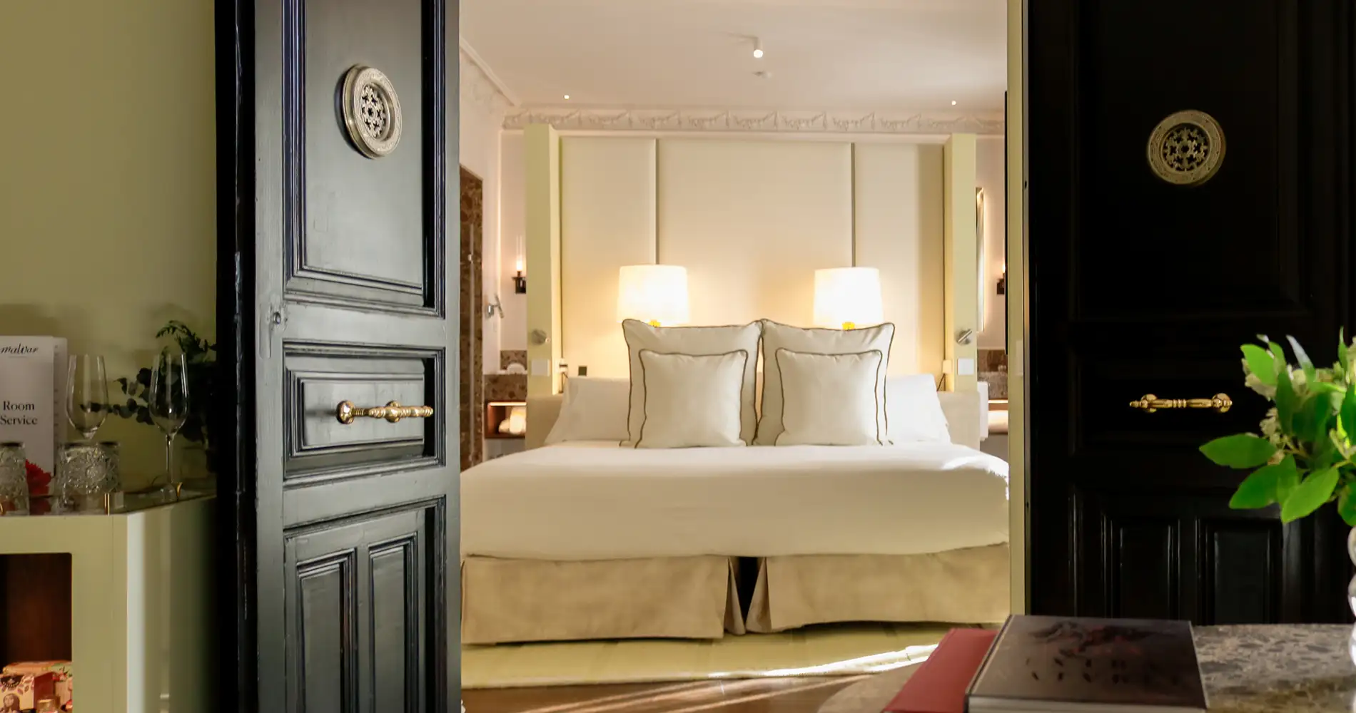 Habitaci&oacute;n de hotel luminosa con cama doble y almohadas, vista desde el pasillo