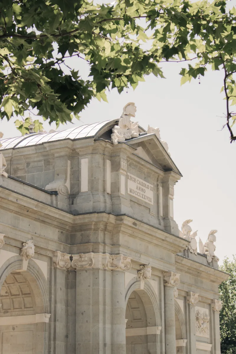 Estatua en el front&oacute;n de un edificio de piedra, entre hojas verdes