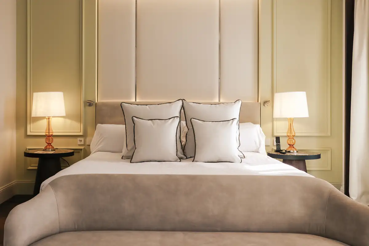 Dormitorio elegante con cama doble, almohadas y dos l&aacute;mparas de mesa