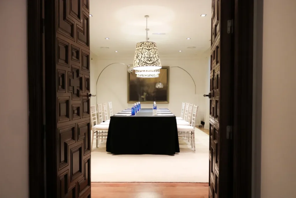 Sala elegante con mesa, sillas y l&aacute;mpara de techo en hotel o evento