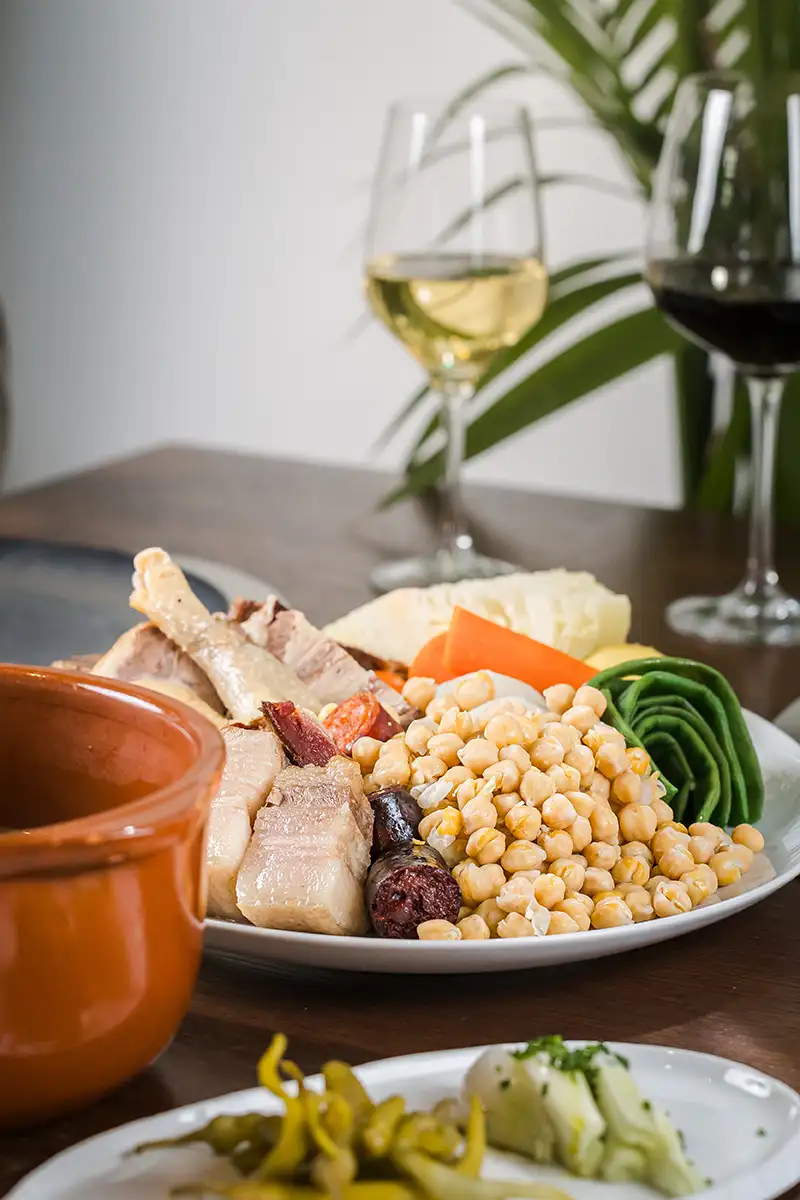 Plato de verduras y pescado con granos de ma&iacute;z, vino y recipientes de cer&aacute;mica