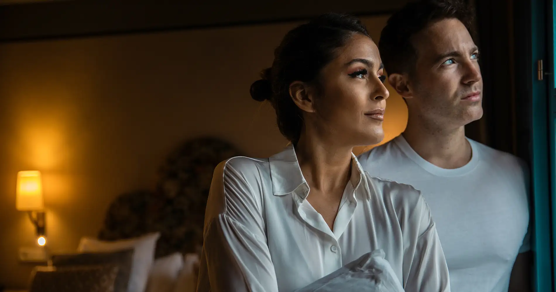 Mujer y hombre con mirada seria en una habitaci&oacute;n con luz c&aacute;lida