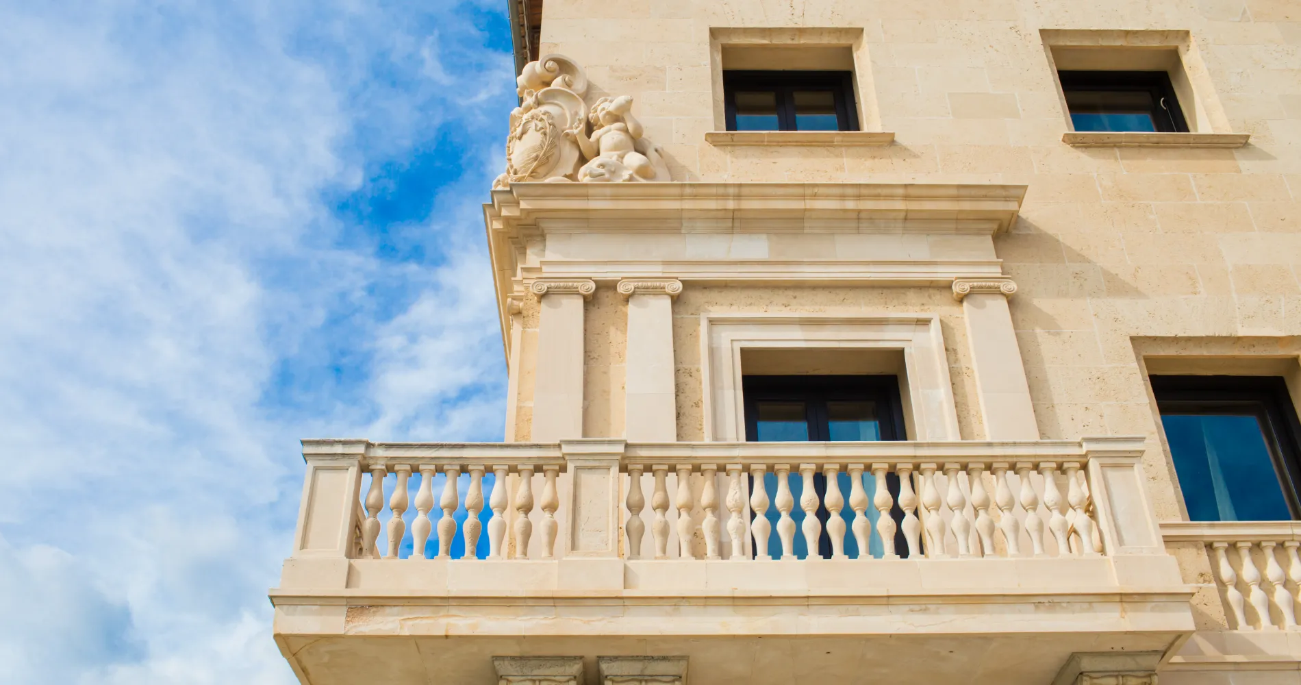 Fachada de edificio cl&aacute;sico de piedra con columnas y detalles ornamentales