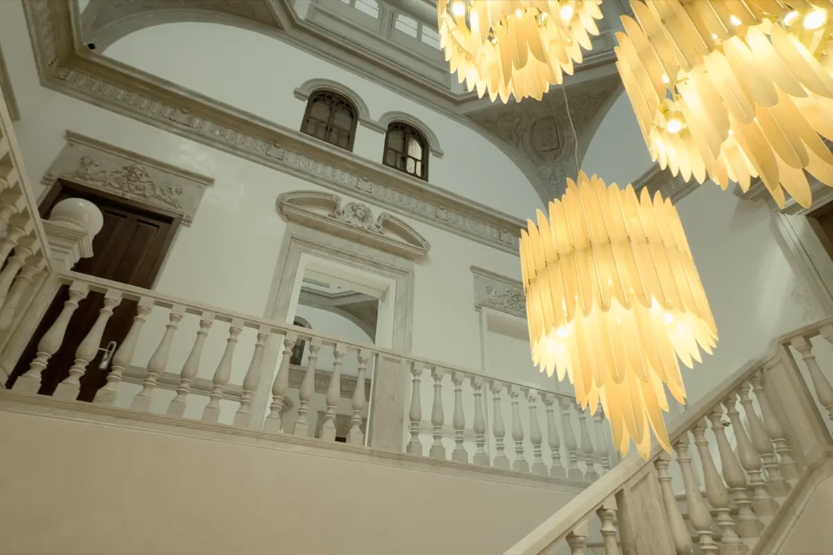 Interior de edificio cl&aacute;sico con l&aacute;mparas colgantes amarillas y detalles ornamentales