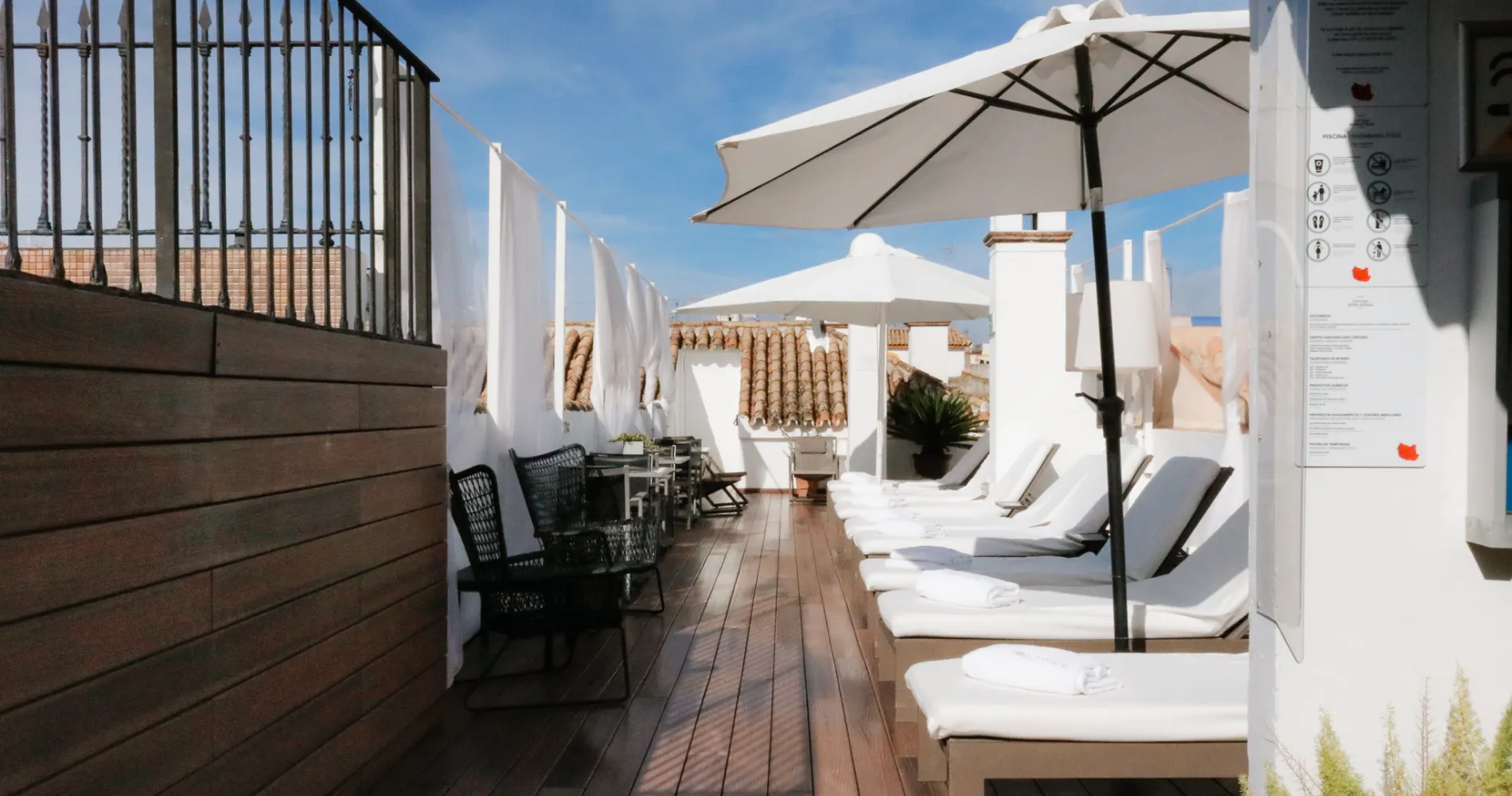 Terraza con tumbonas blancas y sombrillas bajo cielo azul