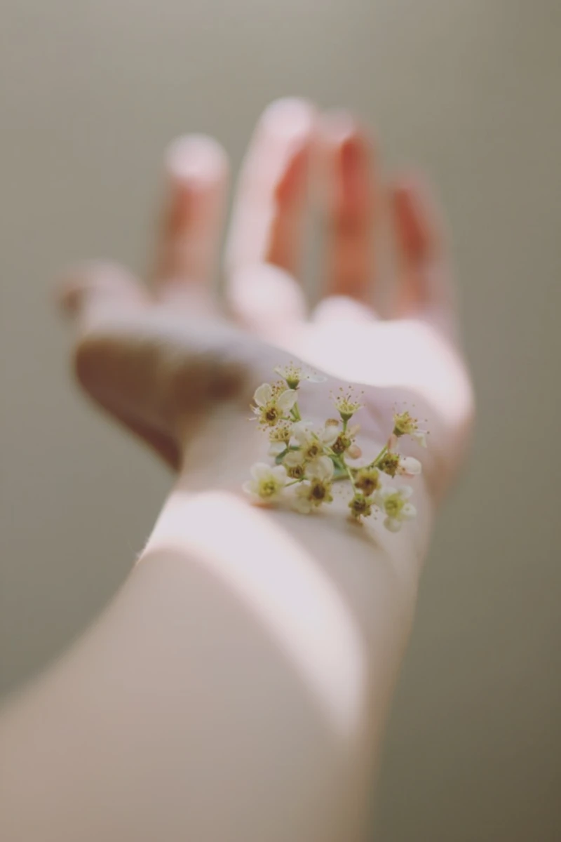 Mano blanca con flores peque&ntilde;as amarillas en el centro, desenfoque suave