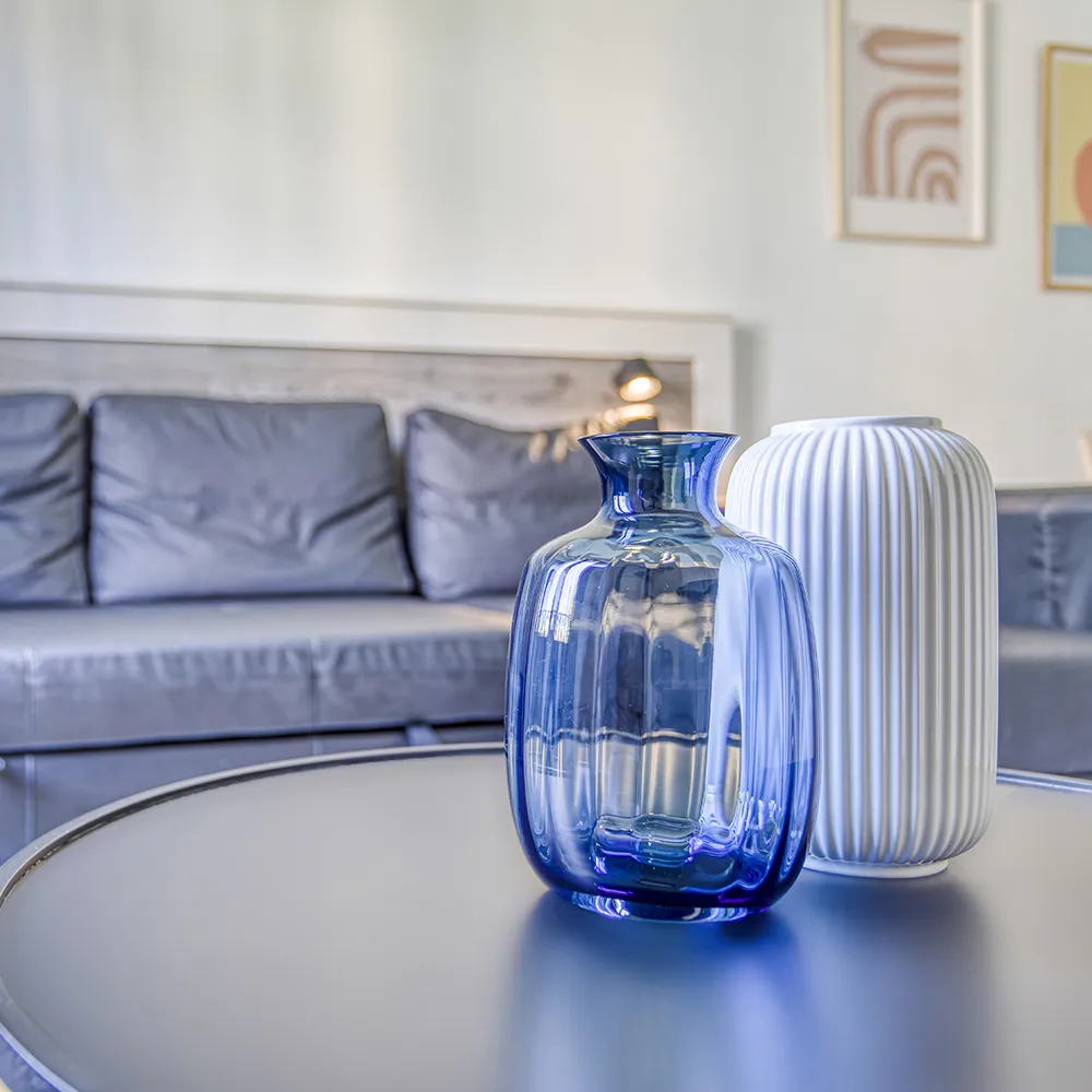 Jarrones azul y blanco sobre una mesa; sof&aacute; gris al fondo.