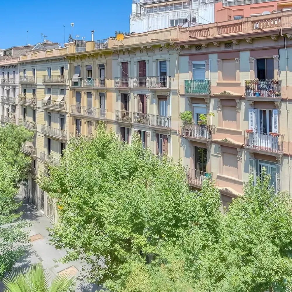 Edificio de apartamentos con balcones y &aacute;rboles al frente.