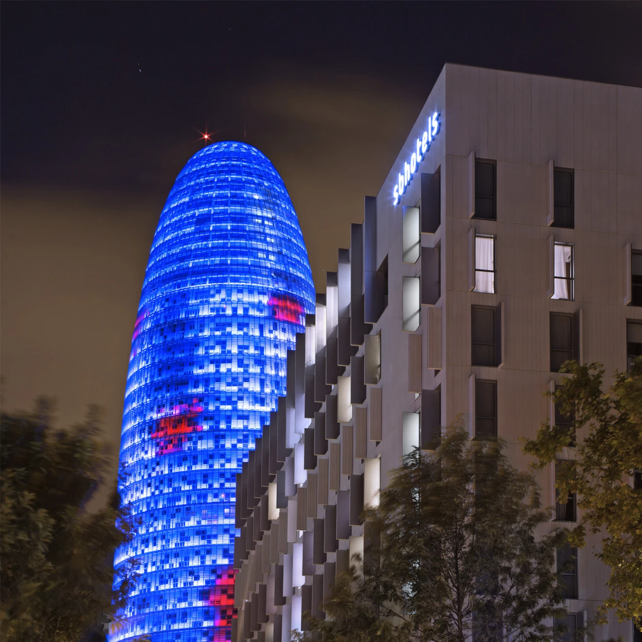 Illuminated modern skyscraper at night with colorful lights in an urban city setting.