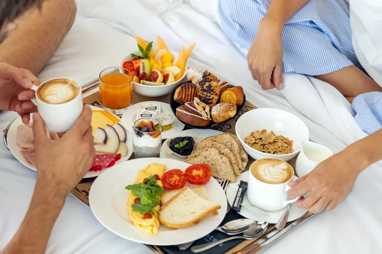 A cozy breakfast in bed with coffee, fresh fruits, and pastries.