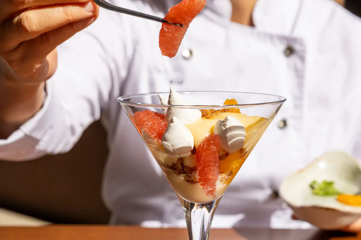 A delicious fruit parfait dessert with grapefruit and cream served in a glass.