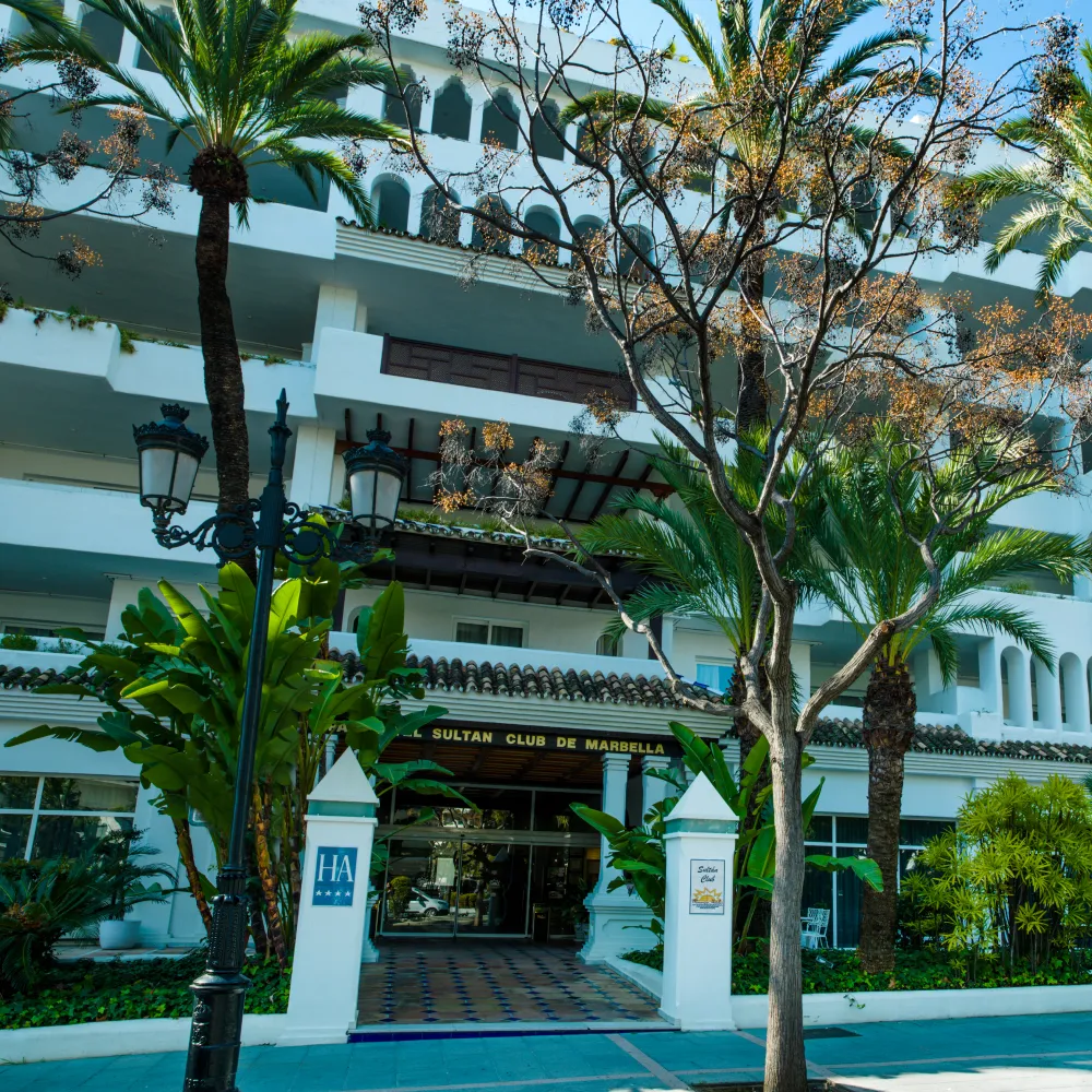 Entrada del Sultan Club de Marbella con palmeras y fachada blanca.
