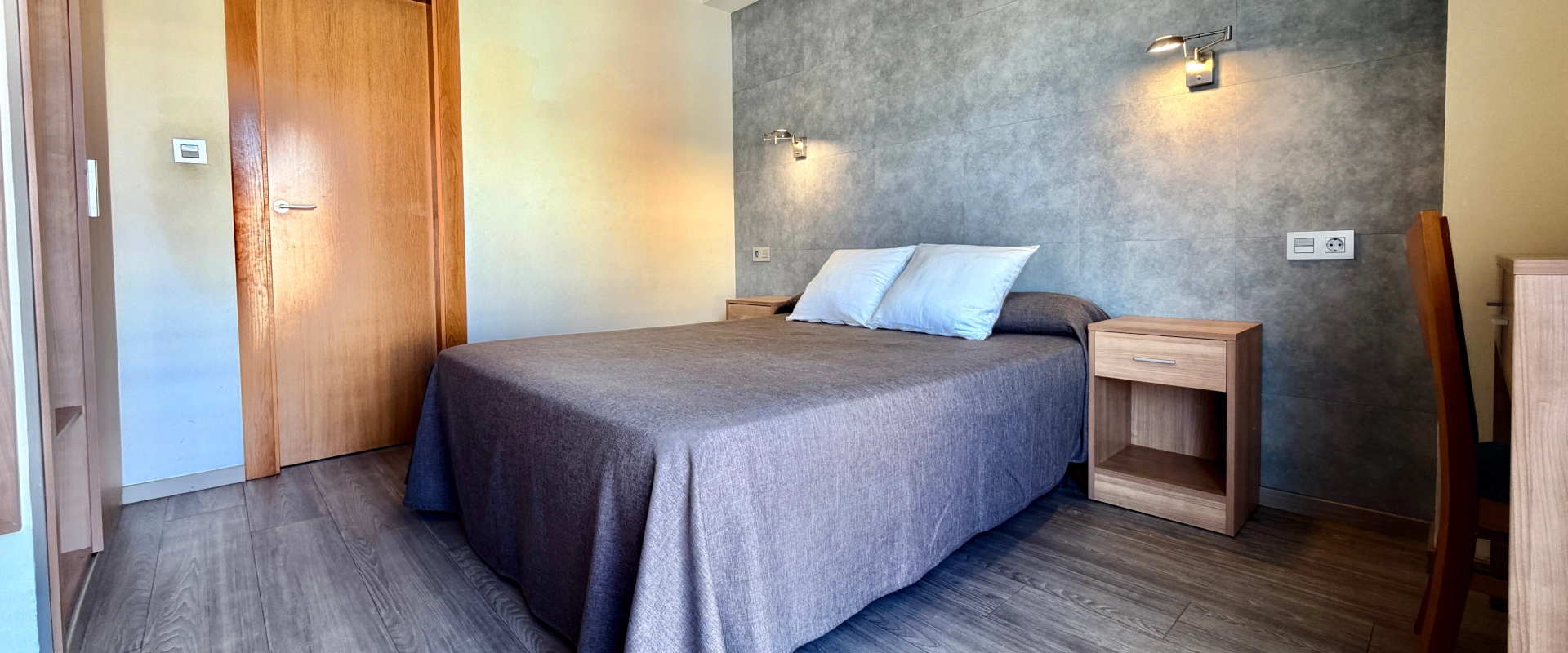 habitacion doble con suelo de parket y pared de cabezal gris