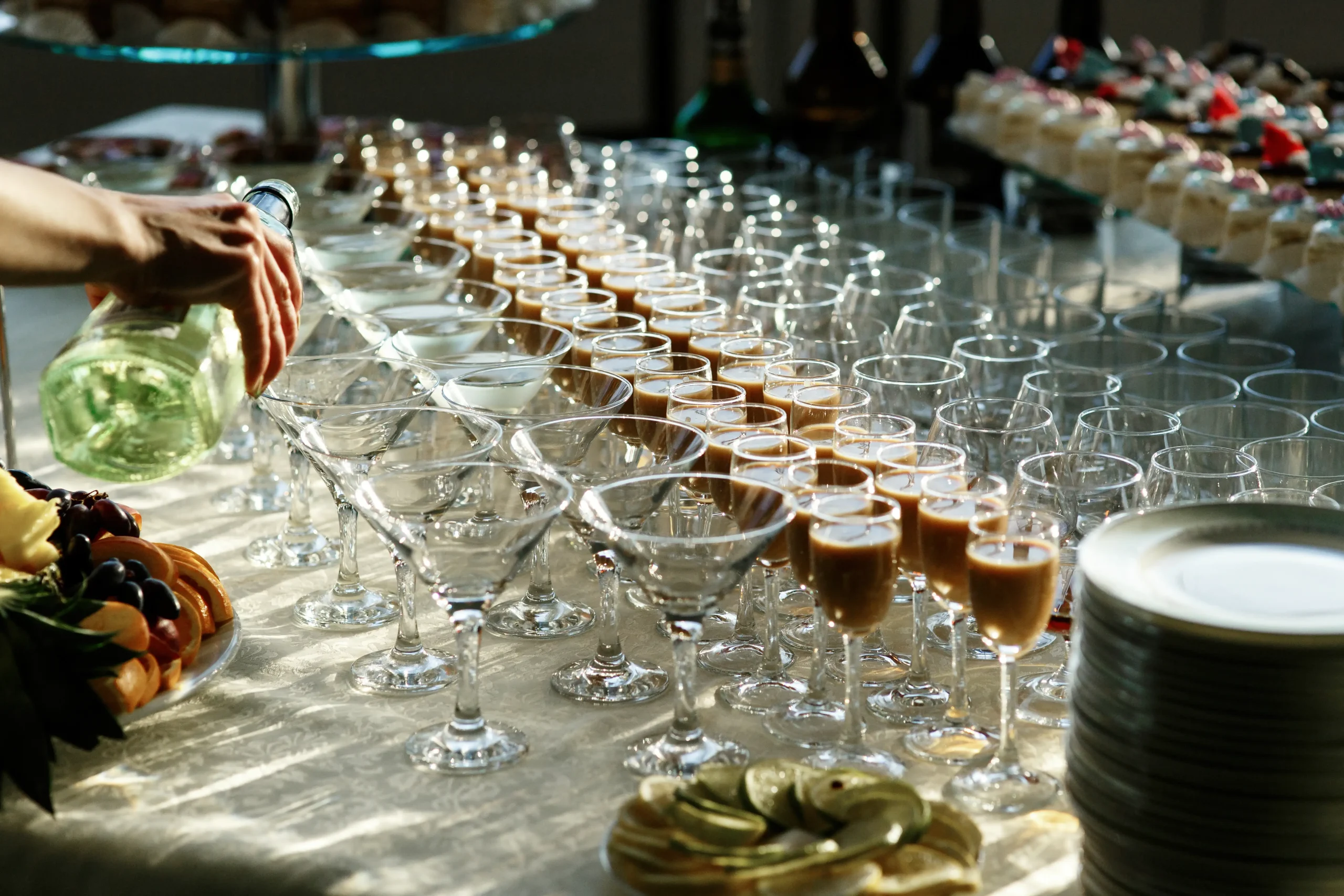 Una mano sirve vino en una mesa con copas y aperitivos.