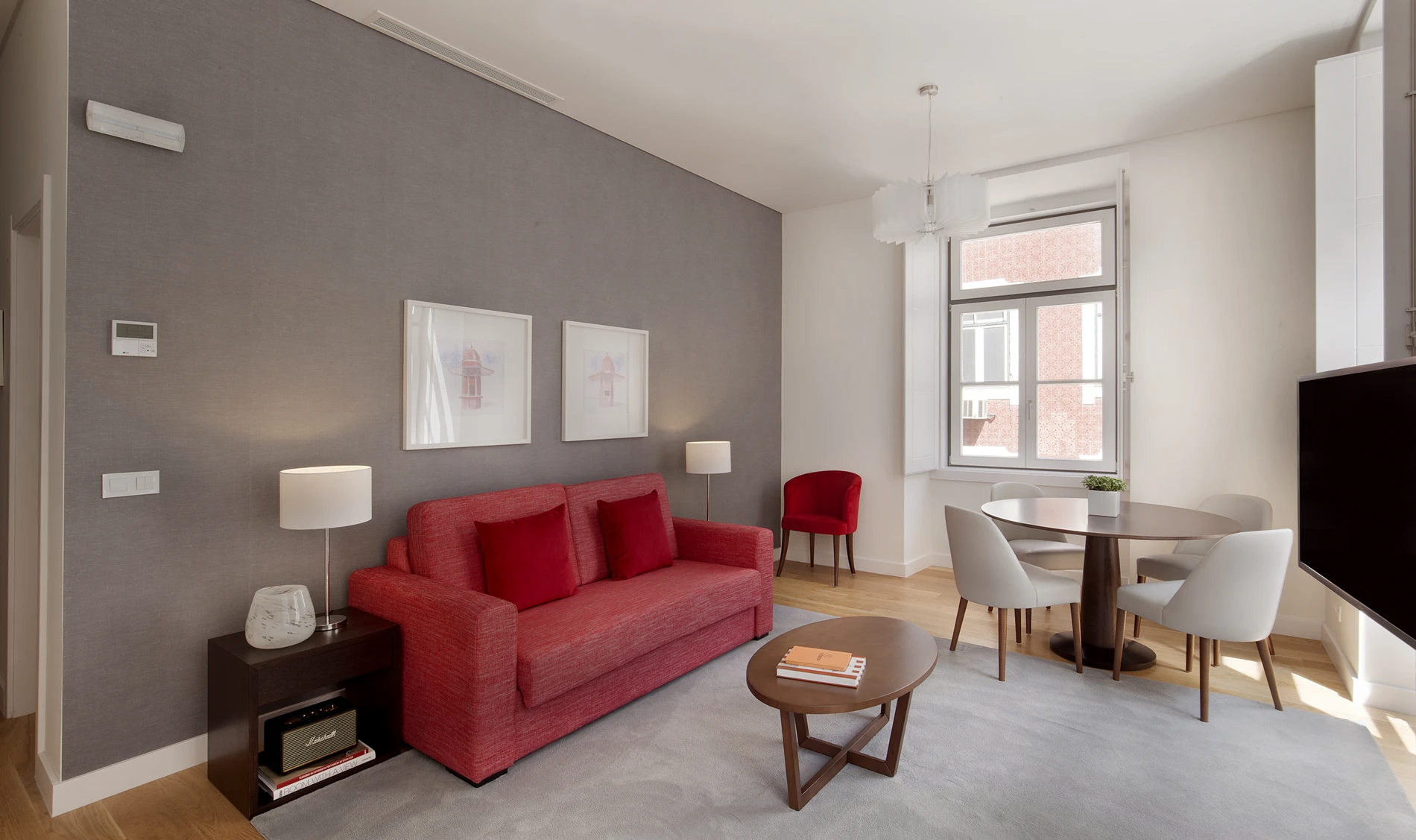 Sala moderna com sof&aacute; vermelho, mesa de centro e mesa de jantar.