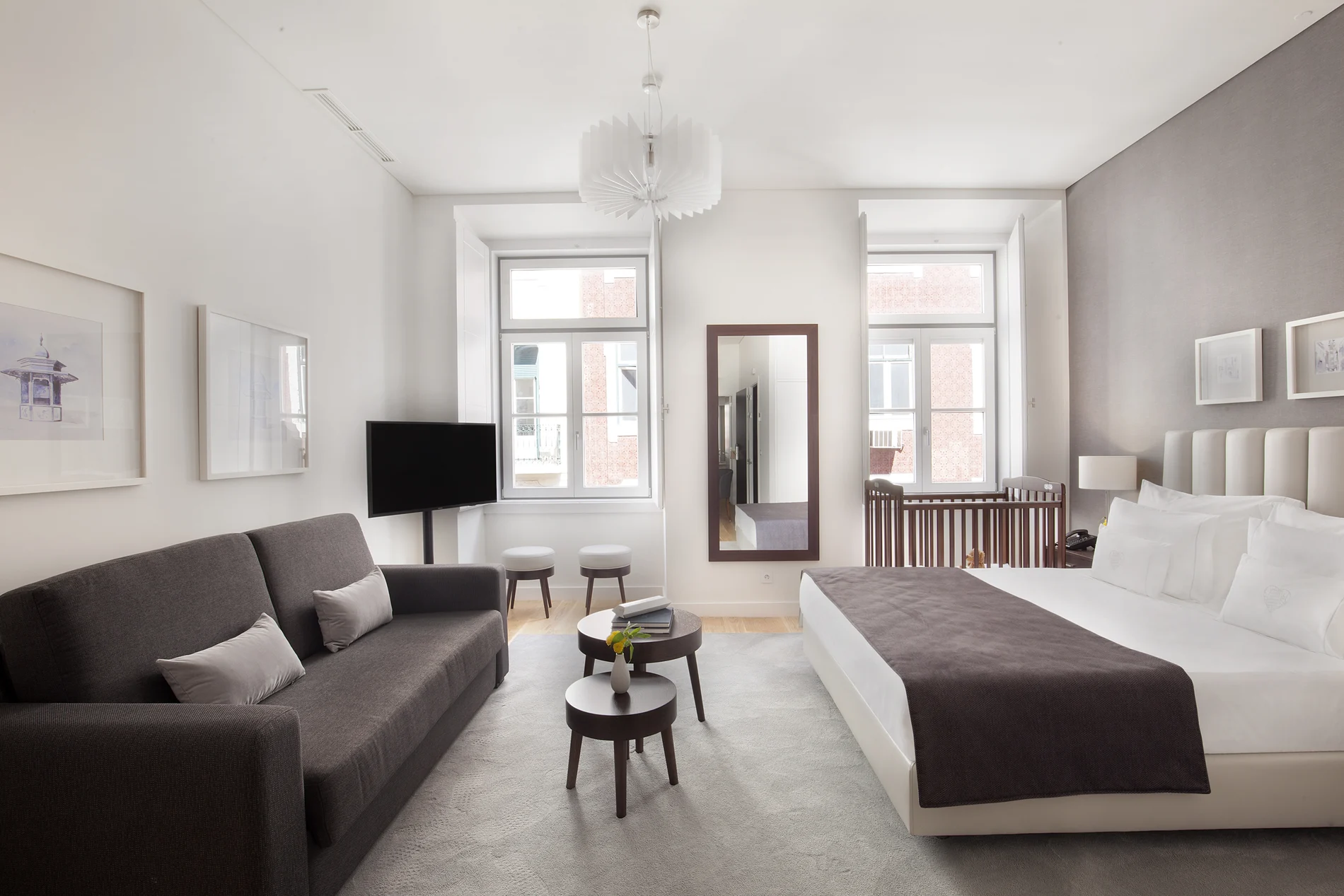 Quarto de hotel moderno com cama, sof&aacute; e decora&ccedil;&atilde;o em tons neutros.