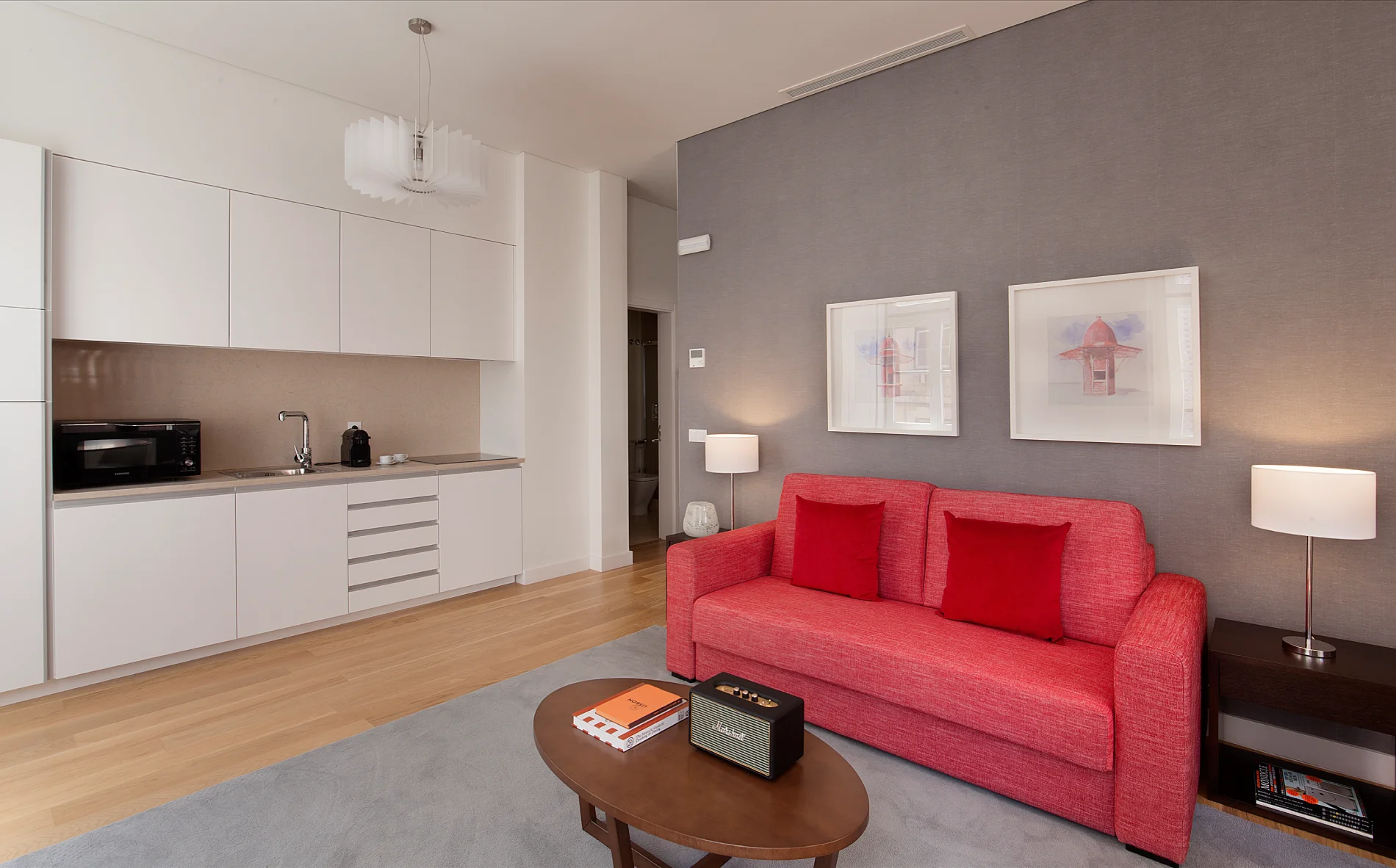 Sala moderna com sof&aacute; vermelho e cozinha integrada.