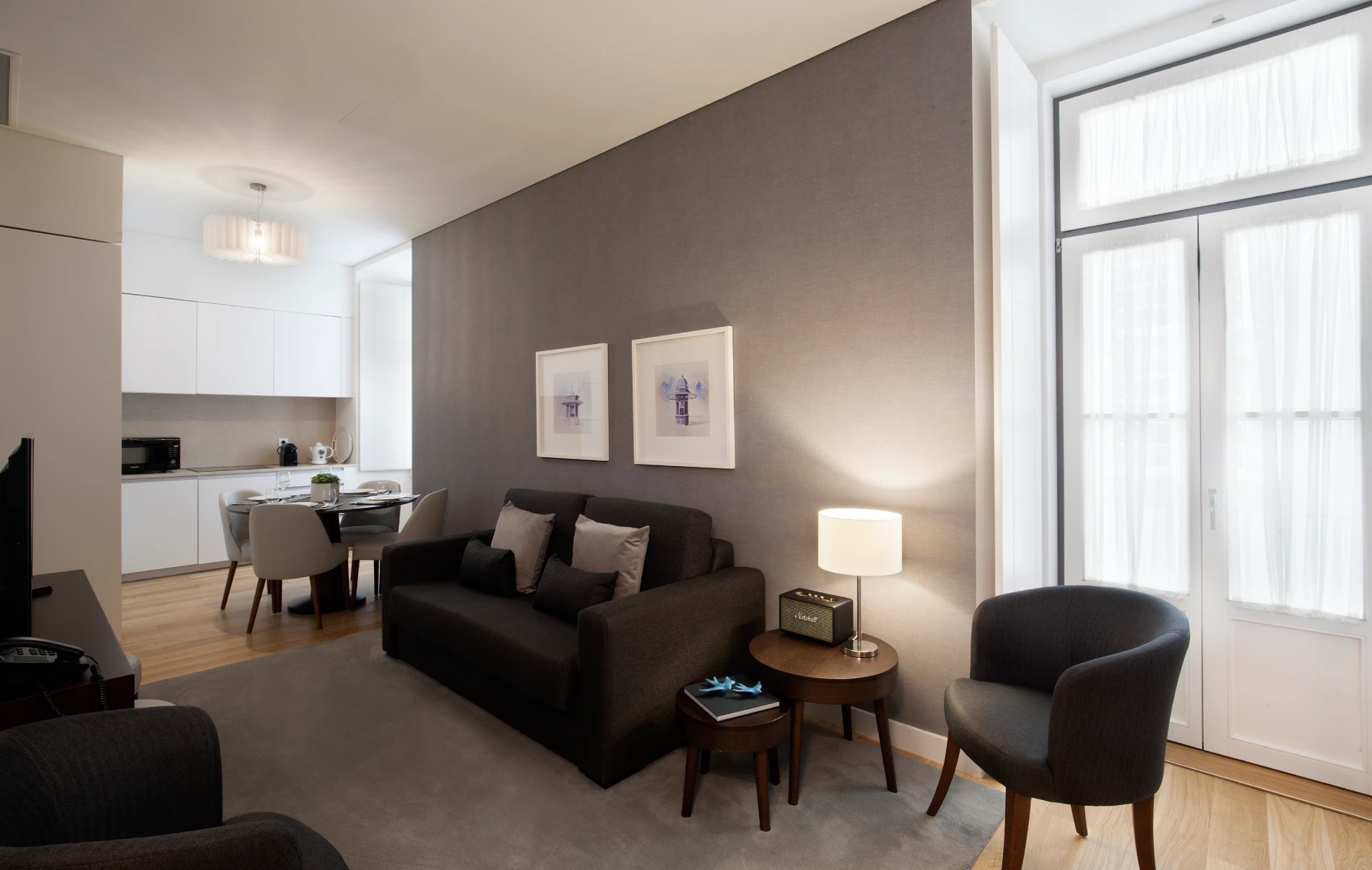 Sala de estar moderna com sof&aacute; escuro, mesa e lumin&aacute;ria.