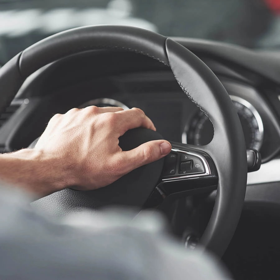 M&atilde;o no volante de um carro moderno, painel de controle vis&iacute;vel.