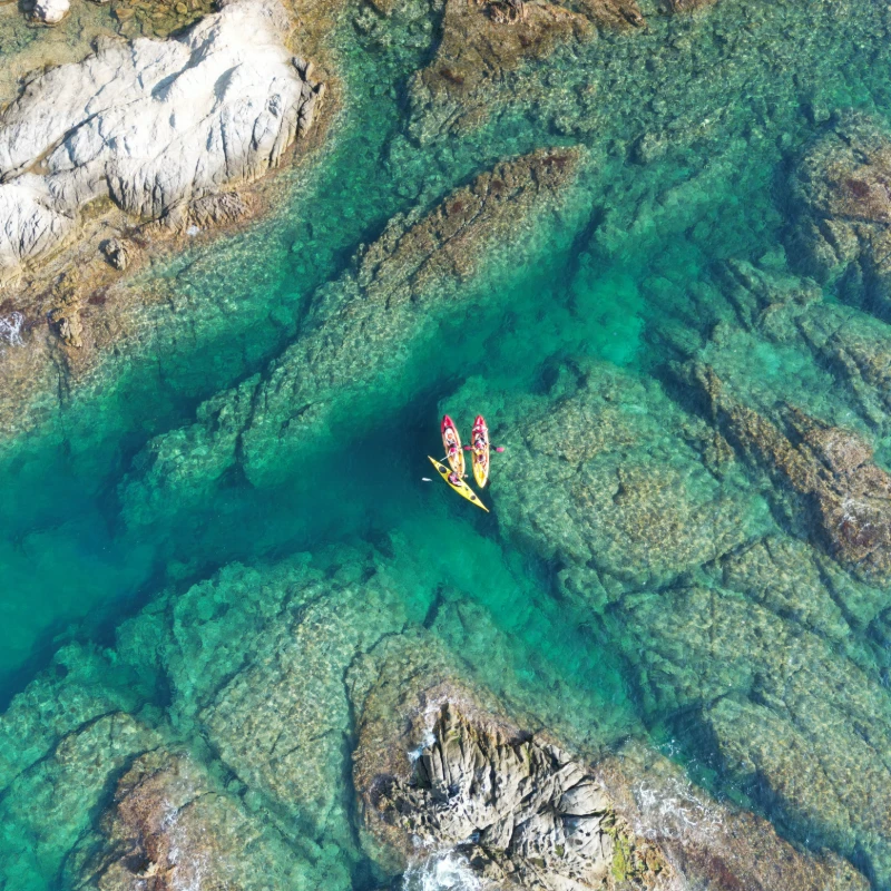 Dos kayaks en aguas cristalinas rodeadas de formaciones rocosas.