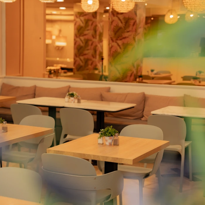 Restaurante moderno y acogedor con mesas de madera, sillas grises y decoraci&oacute;n con plantas.